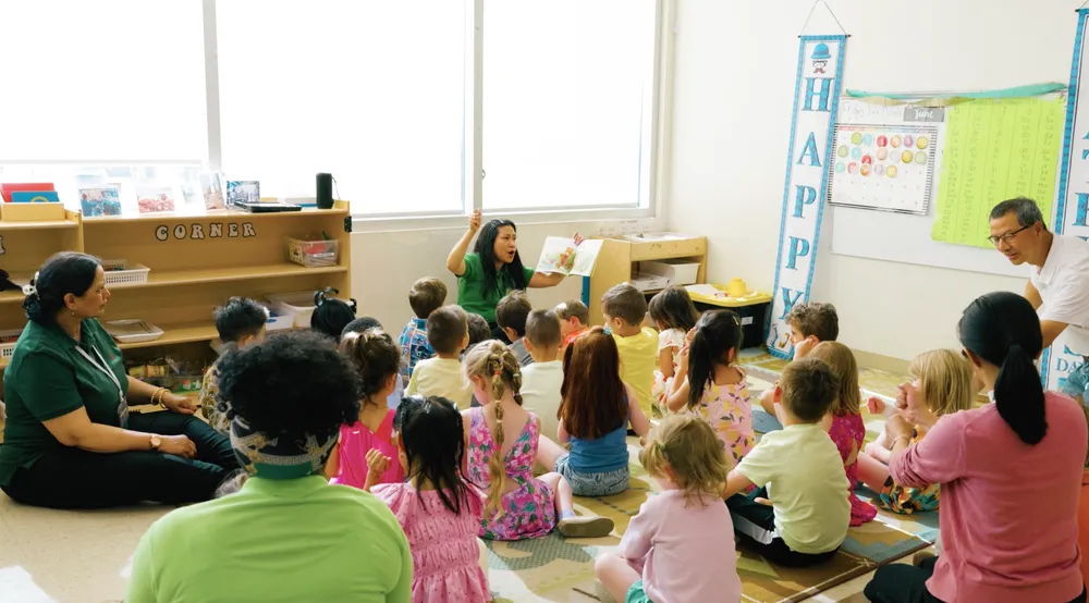 Children sitting on a carpet for circle time with their educators