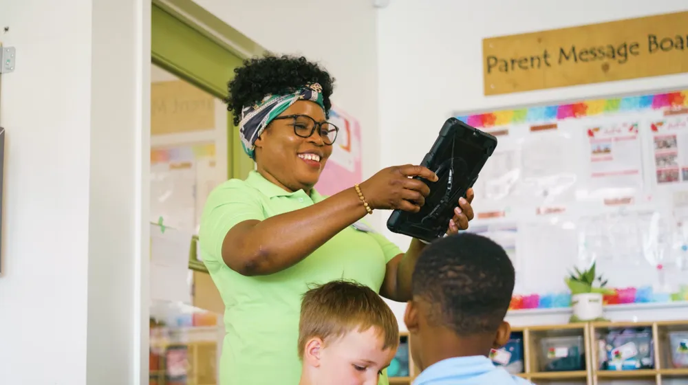 An educator and a child holding a tablet together