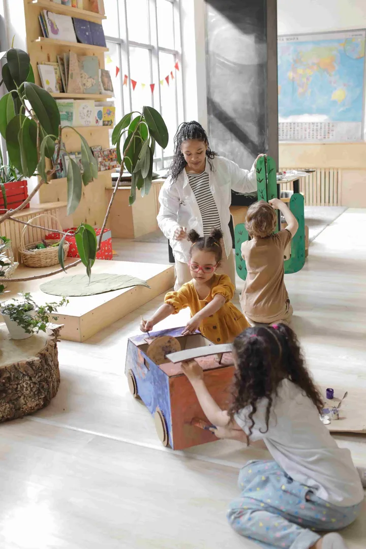 An educator leading pretend play with cardboard cars
