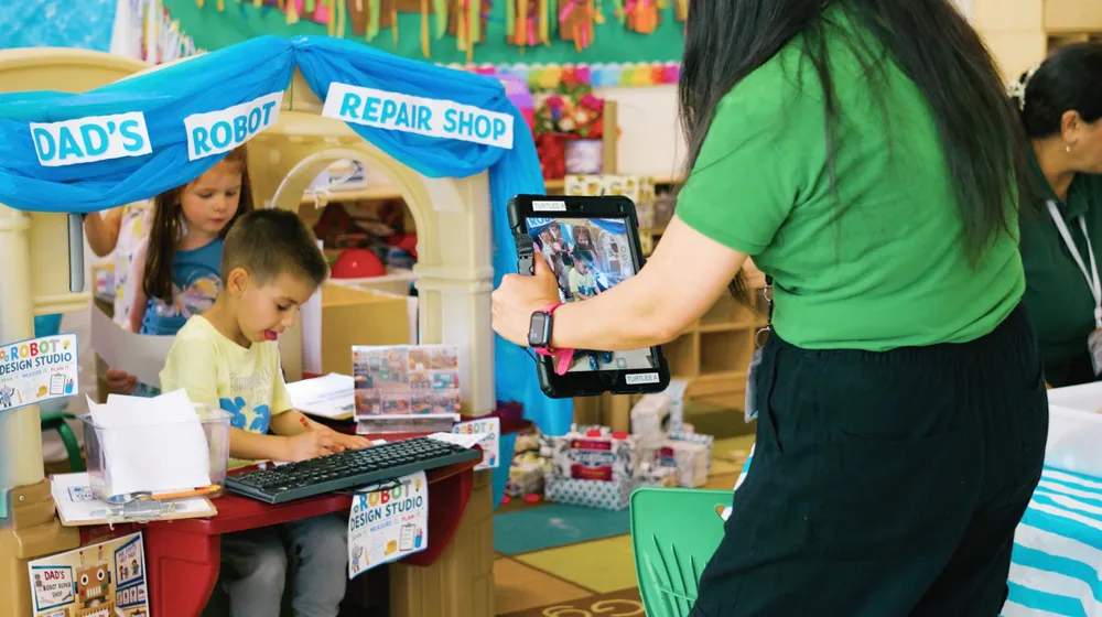 An educator taking a photo of children playing at a pretend shop