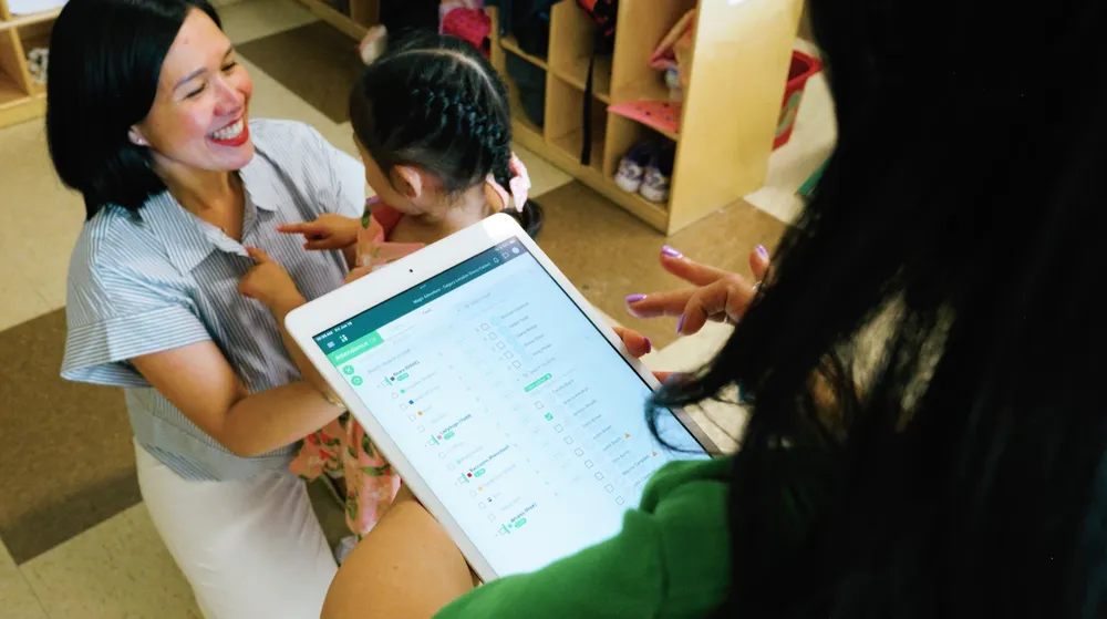 An educator showing children something on a tablet