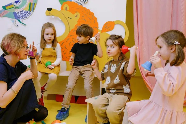 An educator working with a small group of children at a classroom table