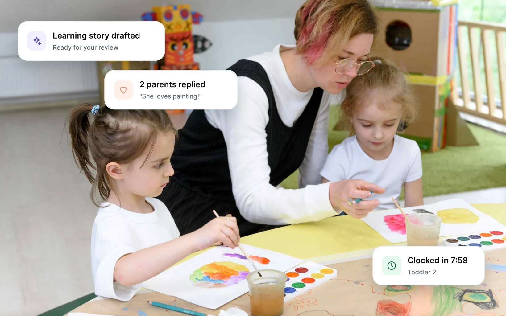 An educator helping two girls paint with watercolours, with app cards for a drafted learning story, parent replies and a staff clock-in