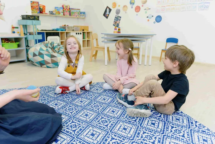 Children sitting in a circle on a play mat during circle time