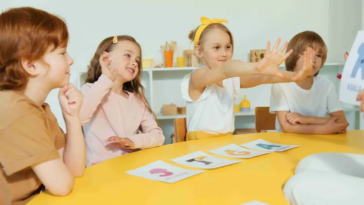 Children learning letters with animal flashcards at a yellow table
