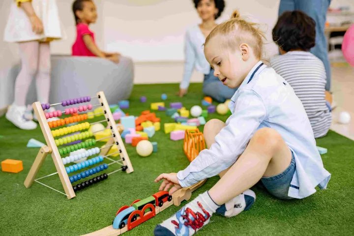 Children stretching to touch their toes on a road-map rug in their classroom