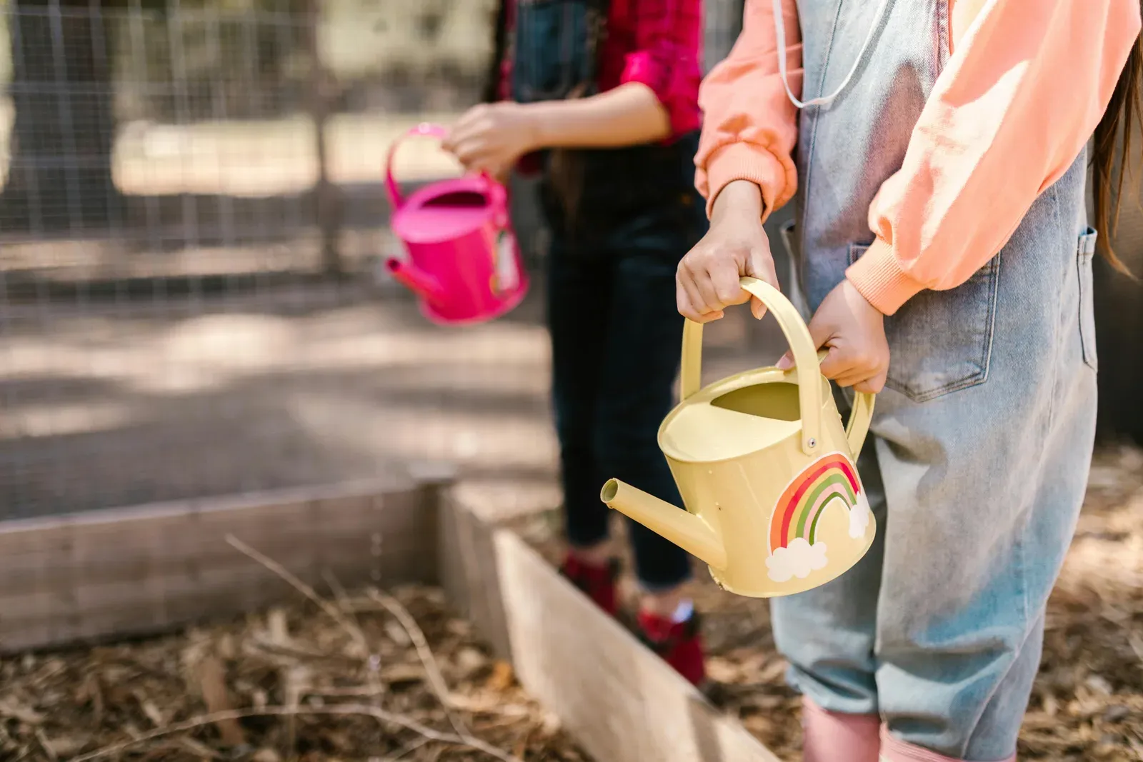 Children with watering cans, gardening outside during Spring.