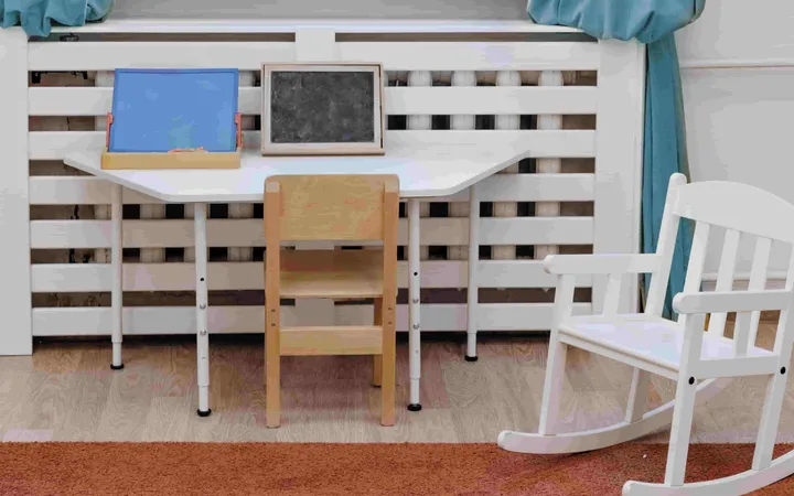 A quiet corner with a child-sized desk, chalkboard and rocking chair by a window