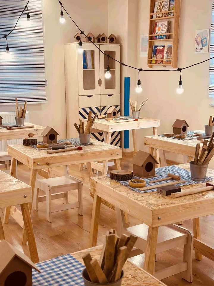 A craft room set up with wooden workbenches and birdhouse projects