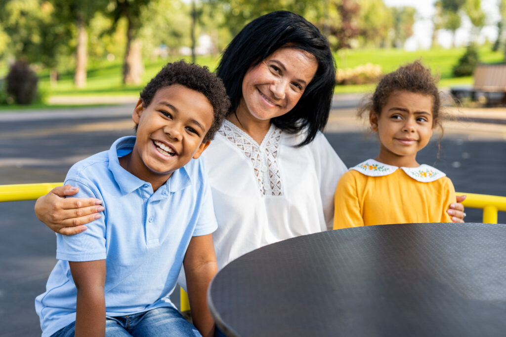 Mom with two kids sitting outside of daycare center and smiling.