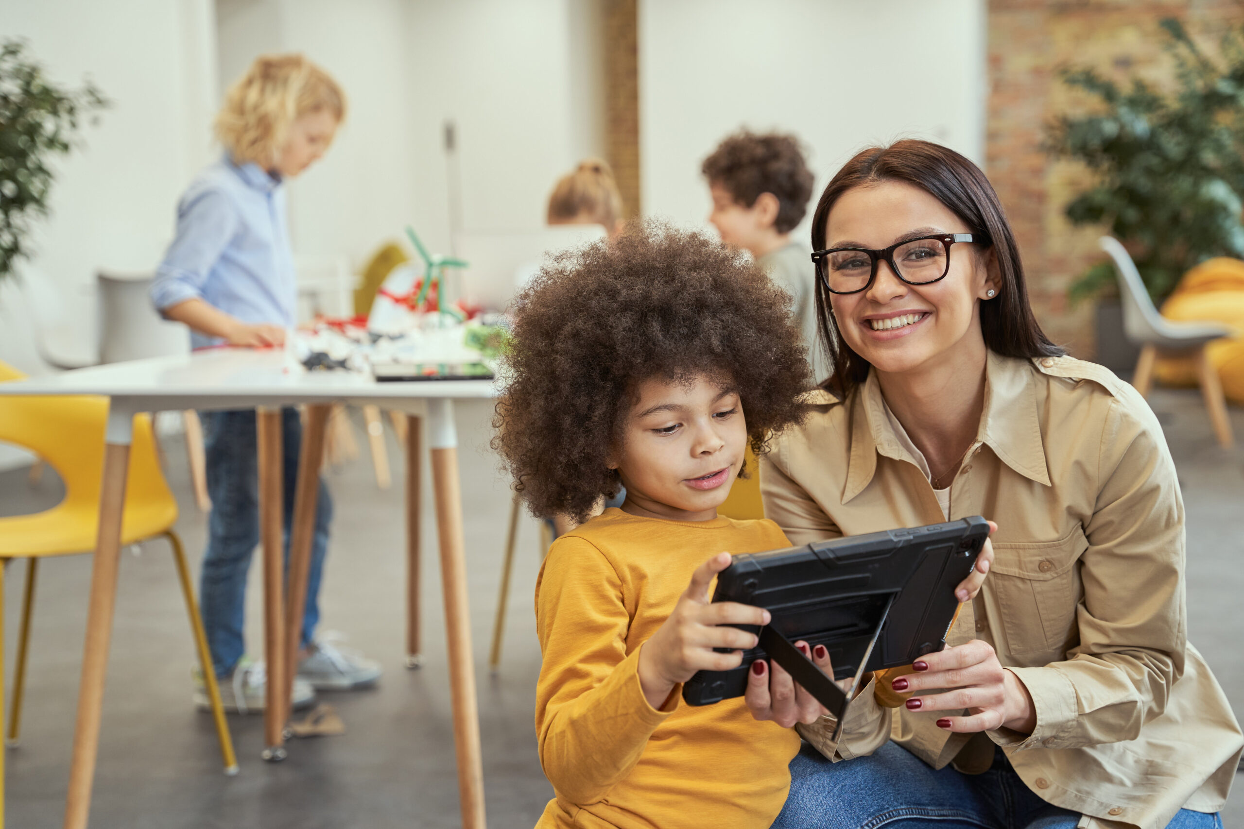 Young female teacher at childcare center with ipad and student.